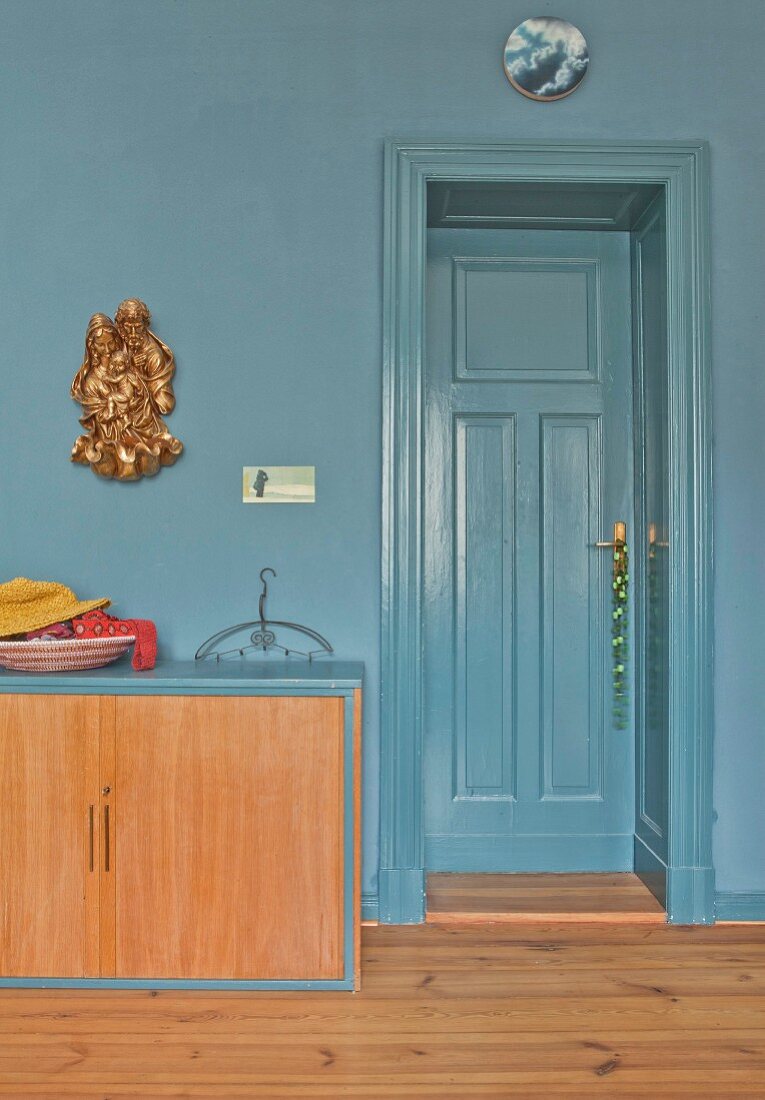 Low sideboard against blue-grey wall and next to door of same colour