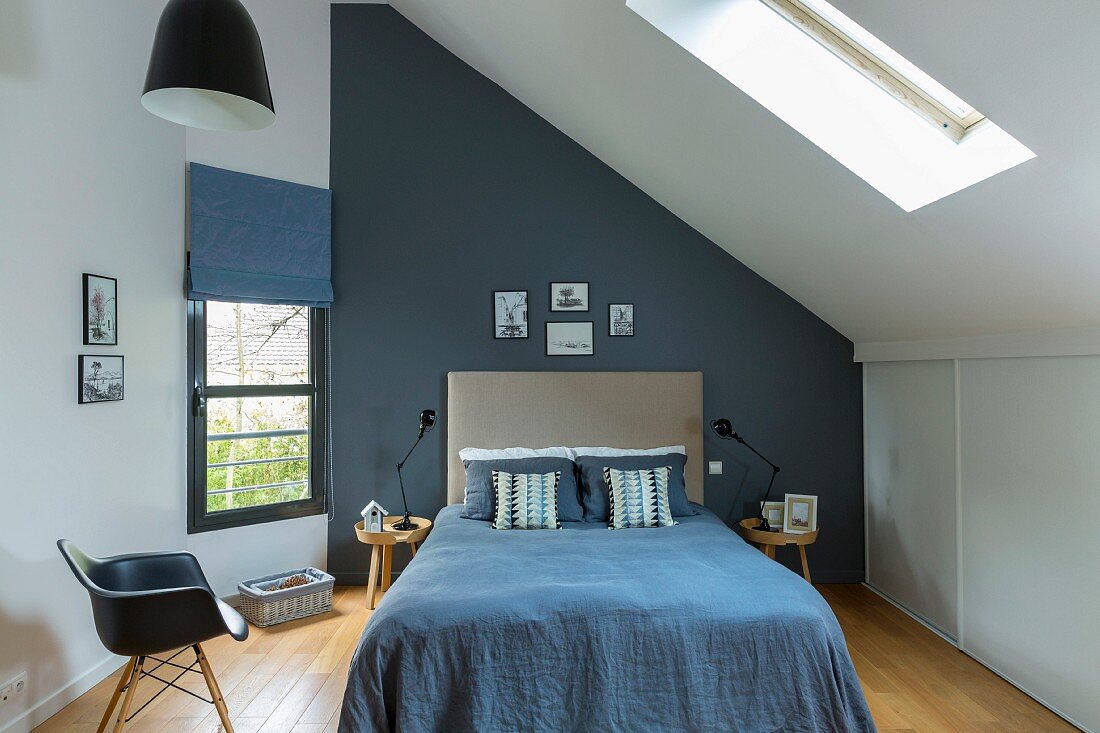 Doppelbett mit blauer Tagesdecke im Dachzimmer