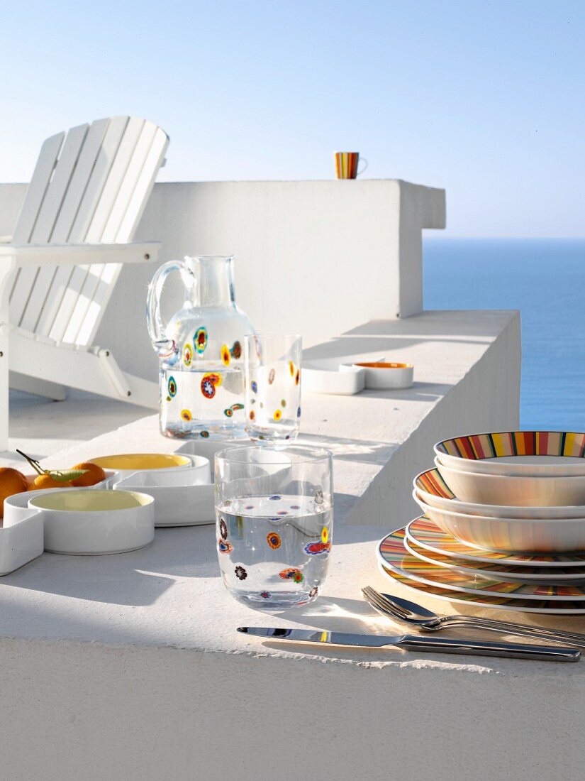 Colourful crockery on white wall with view of sea