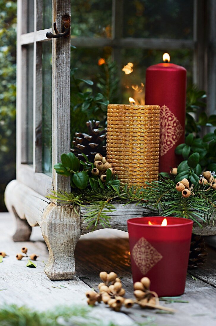 Gold and red candles in lantern decorated with green twigs