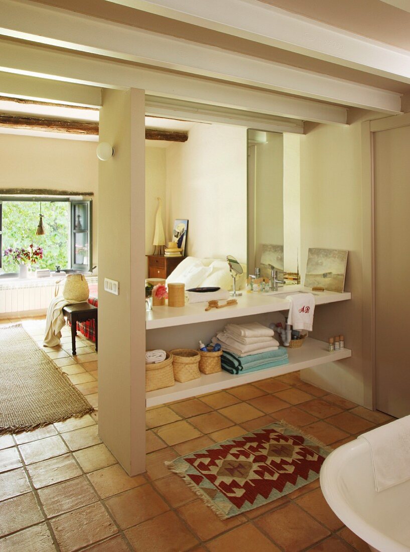Schlichtes Einbauregal mit Waschbecken und Spiegel in Bad Ensuite mit Blick in Schlafzimmer
