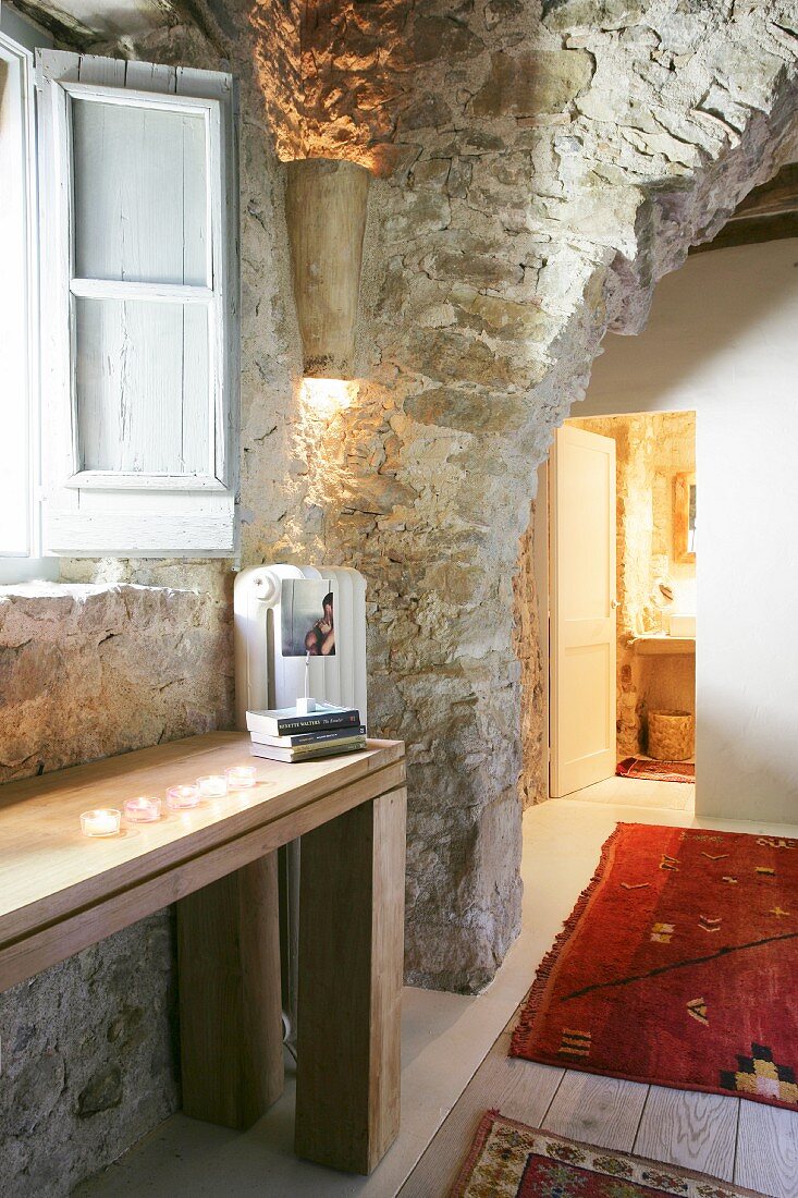 Rustic doorway in restored stone house with view into illuminated bathroom
