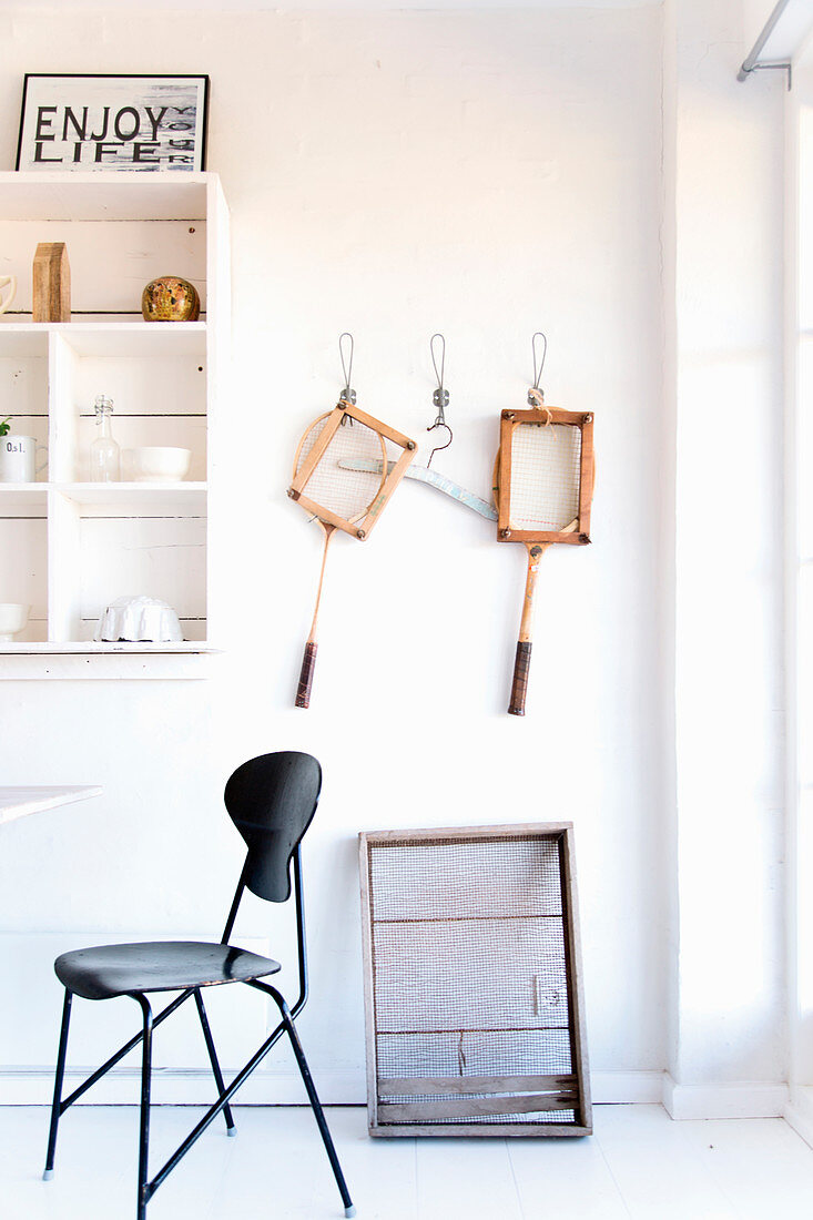 Black classic chair in front of white shelves and vintage utensils on wall
