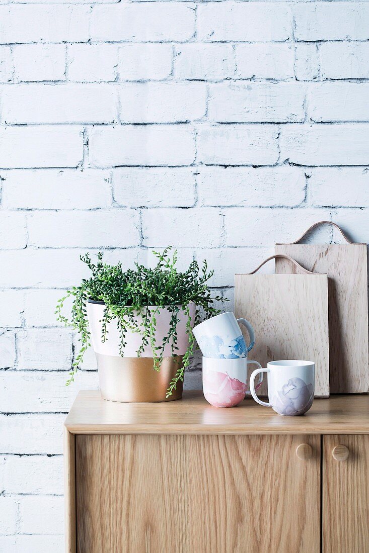 DIY Marmorierte Tassen neben Zimmerpflanze auf Sideboard