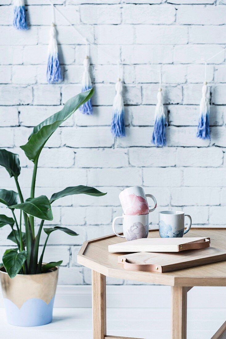 DIY marbled cups on table, houseplant next to white brick wall
