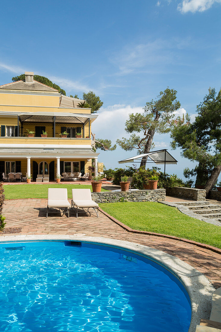 Pool und Liegen im Garten einer mediterraner Villa