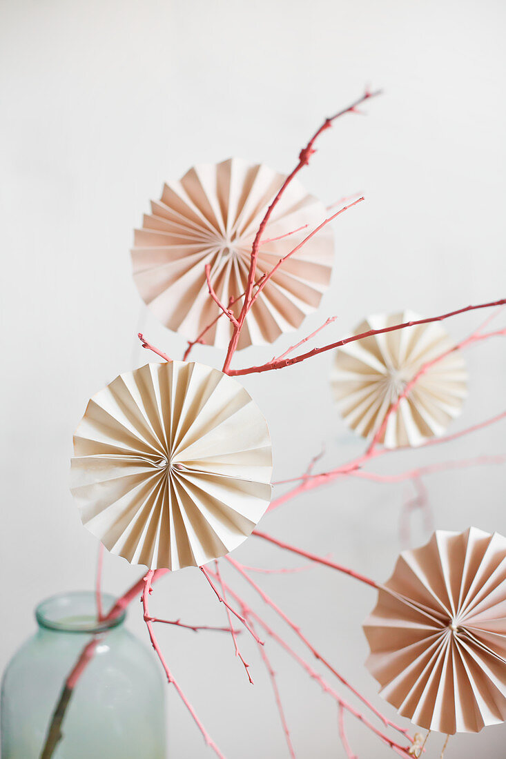 Paper rosettes hung from pink-painted branch