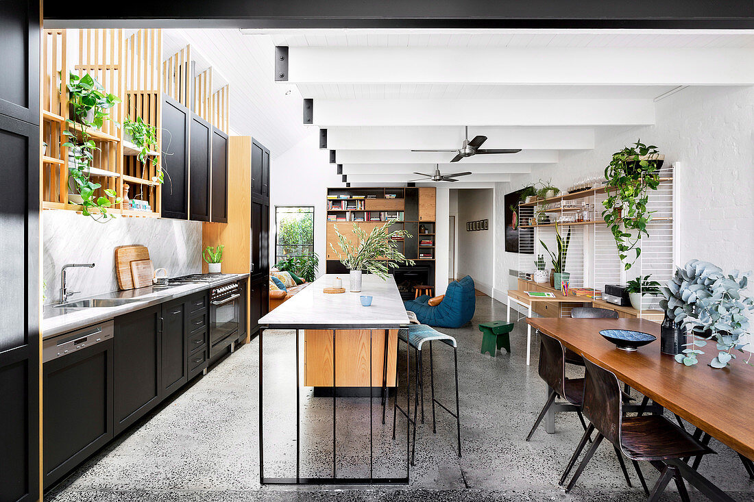 Offener Wohnraum mit Einbauküche, Kücheninsel und Essbereich, im Hintergrund Loungebereich