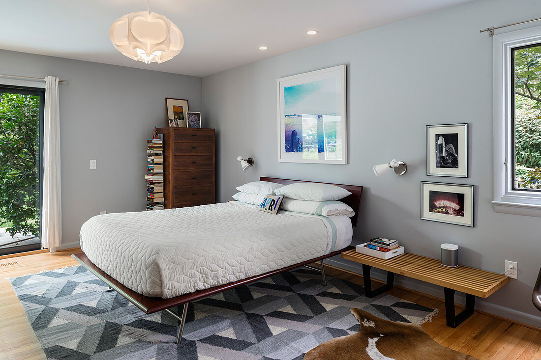 Doppelbett in Schlafzimmer mit hellgrauen Wänden und Gartenzugang