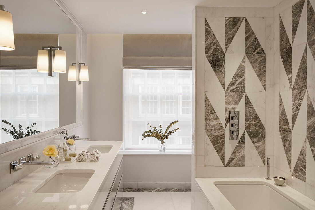 Modernes Bad in Weiß mit grafischem Fliesenmuster über der Badewanne