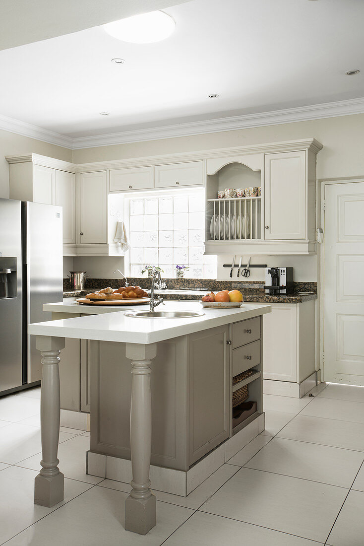 L-shaped counter in renovated country-house-style kitchen in shades of white and taupe