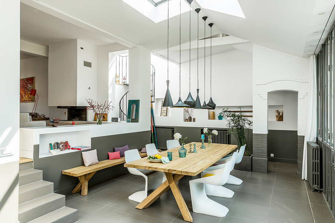 Wooden table and designer chairs in open-plan dining area with grey floor tiles