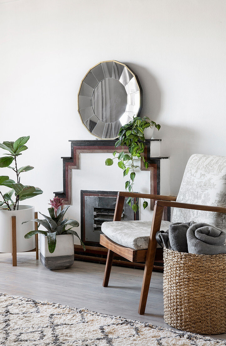 Zimmerpflanzen und Armlehnstuhl vor Kamin mit Spiegel