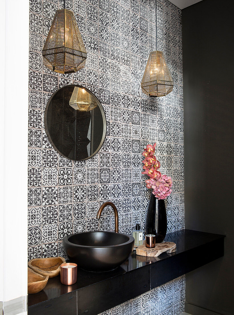 Sink on black washstand in guest toilet with patterned wall tiles