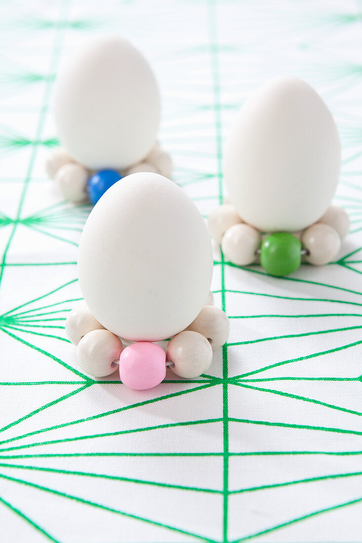 White eggs stood on circlets of wooden beads