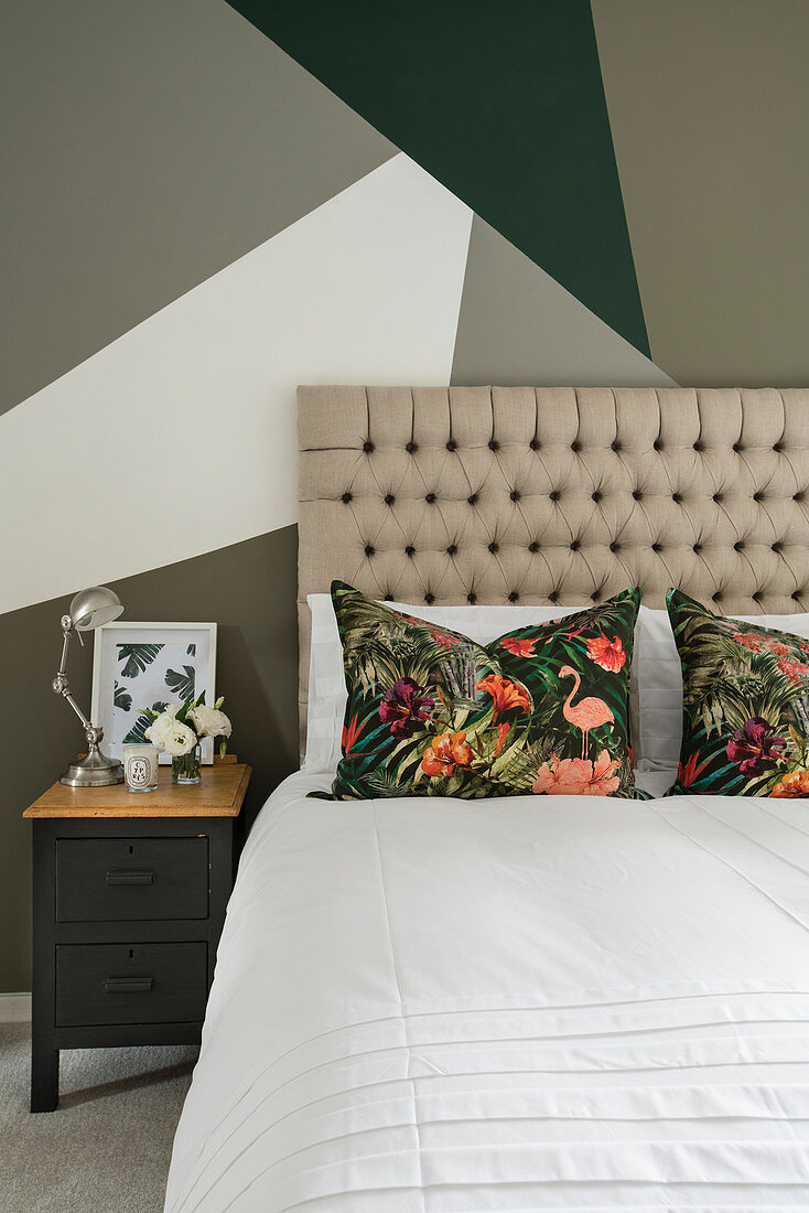 Doppelbett mit hohem Kopfteil vor Wand mit geometrischem Muster im Schlafzimmer