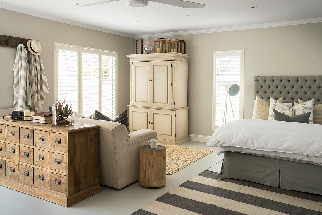 Schlafbereich mit Doppelbett, Kleiderschrank, Ausziehcouch und antikem Apothekerschrank in offenem Wohnraum