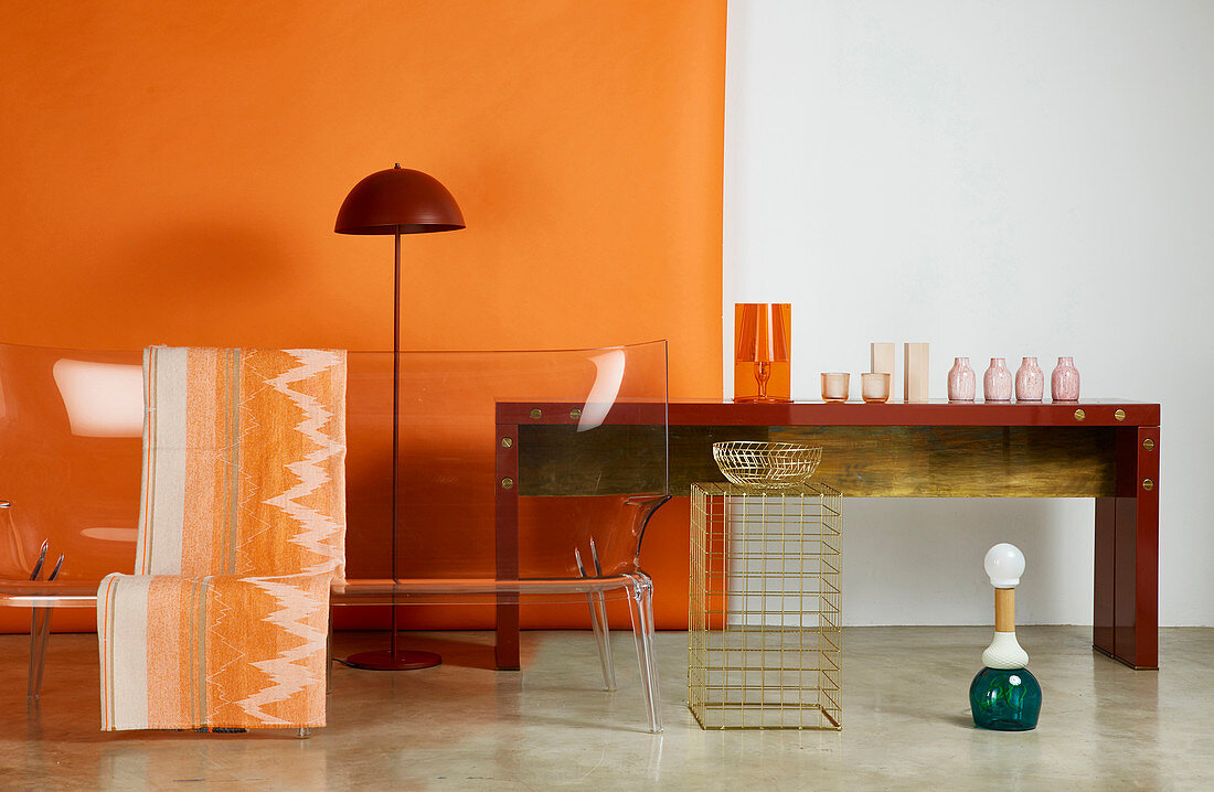 Transparenter Designer-Sofa, Stehleuchte und Konsolentisch mit Vasen vor orangefarbener Wand