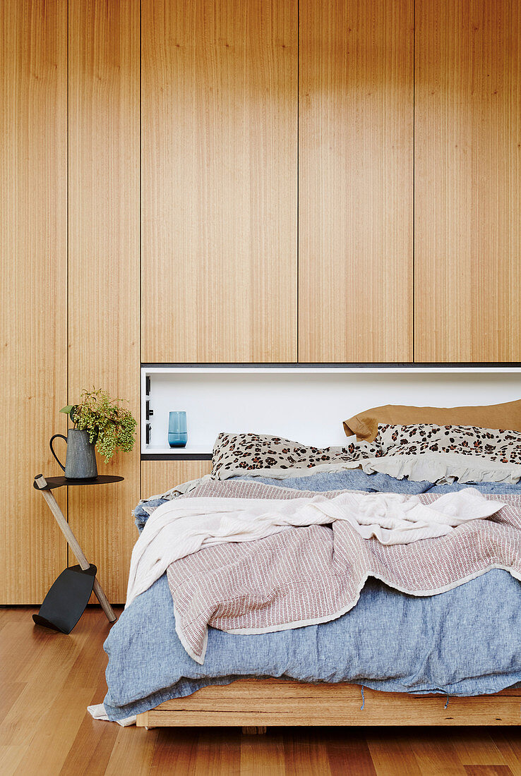 Doppelbett vor Wand mit Holzverkleidung und Nische