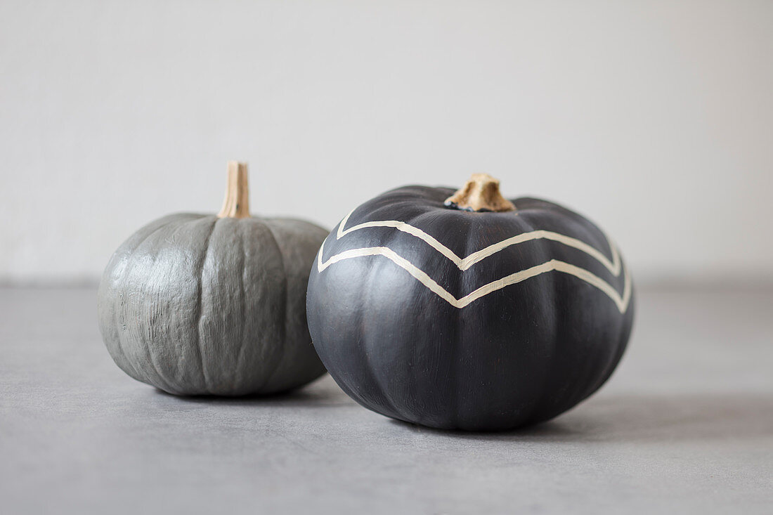 Pumpkins painted grey, one with zig-zag pattern
