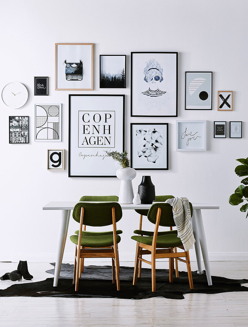 Black and white picture wall above the dining table with green chairs