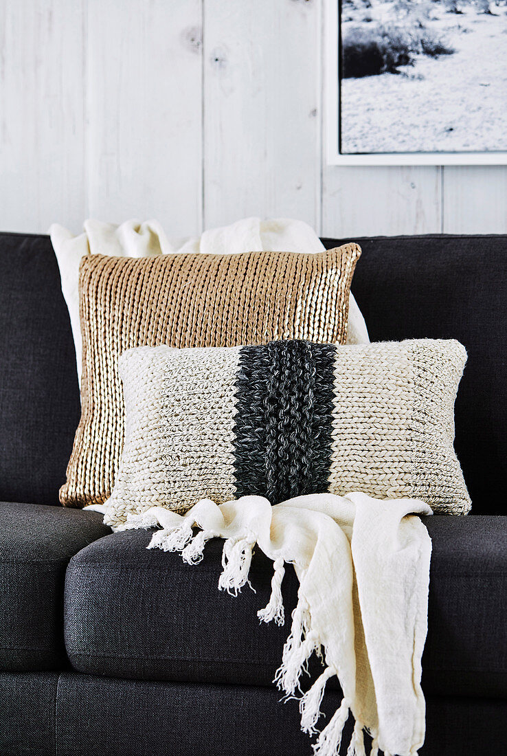 Knitted pillows and plaid with tassels on the sofa