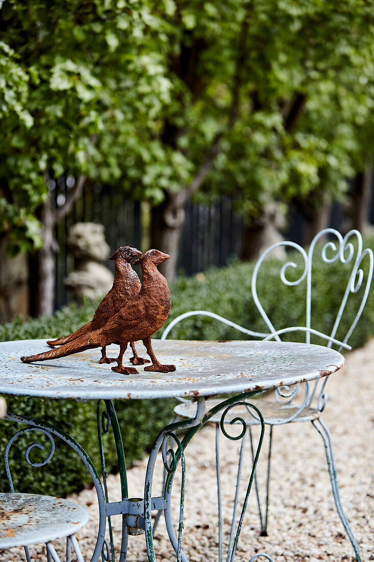 Rusty pheasant figures on a metal table in the garden