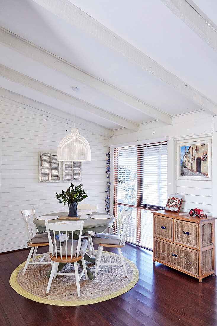 Runder Tisch mit Holzstühlen auf Teppich im Essbereich mit weißer Holzverkleidung