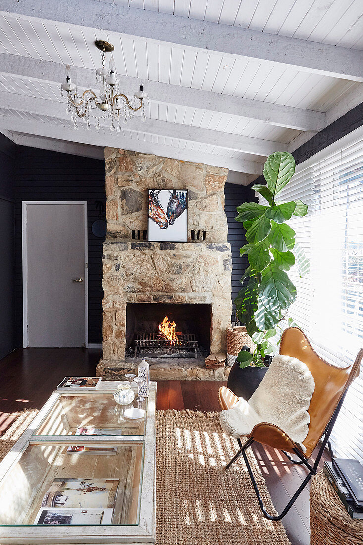 Klassiker Lederstuhl mit Felldecke und Zimmerpflanze vor Kamin im Wohnzimmer