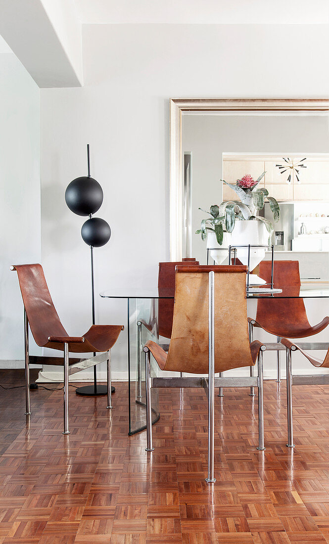 Designerstühle aus Leder und Metall um den Esstisch auf Parkettboden