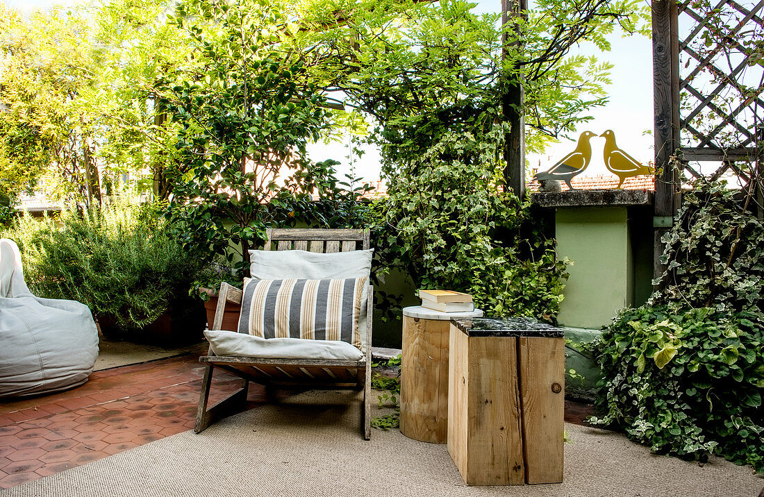 Zwei Holzklötze als Beistelltisch neben einem Sessel auf der Terrasse