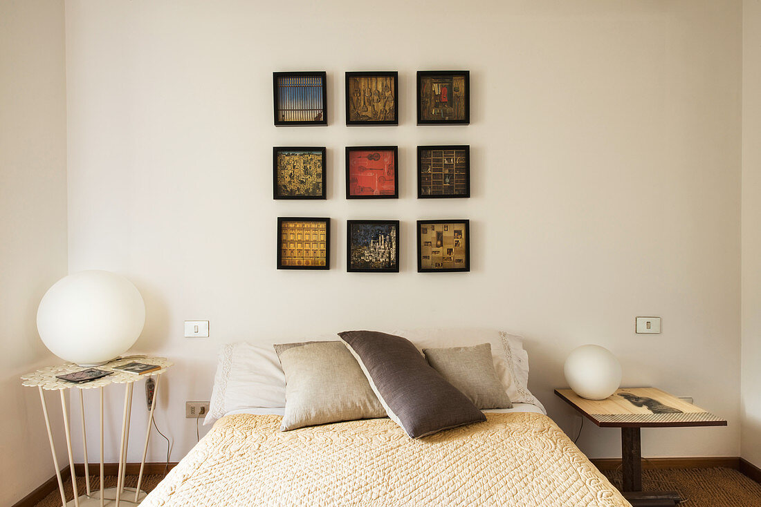 Pictures arranged in a square above a double bed
