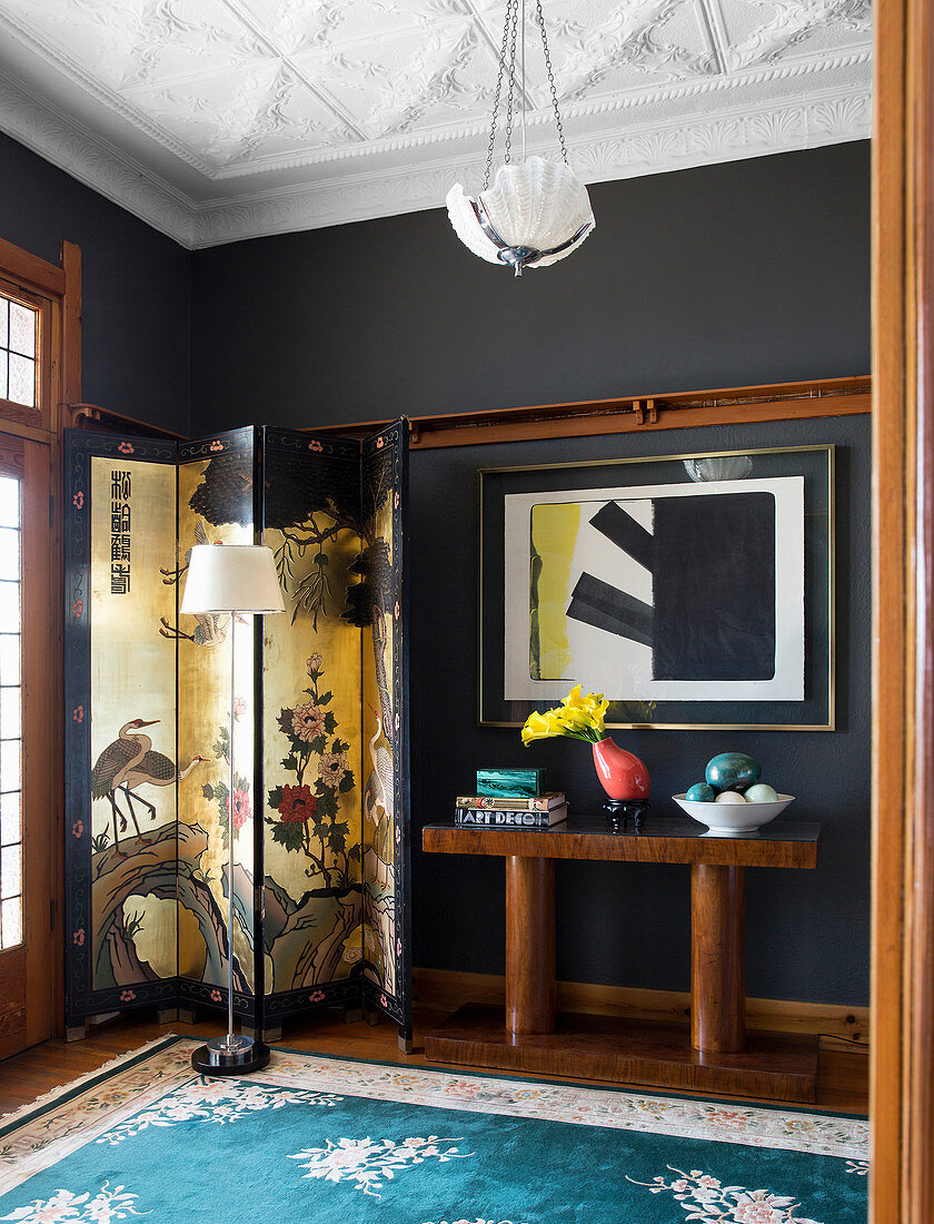 Oriental screen and console table against black wall