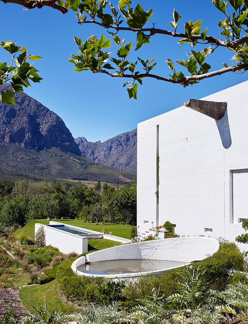 Round rainwater basin and pool in garden against mountain backdrop