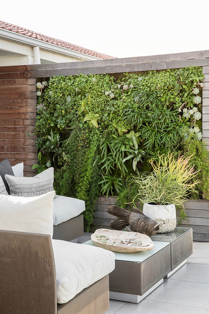Elegante Outdoormöbel und vertikale Bepflanung auf der Terrasse