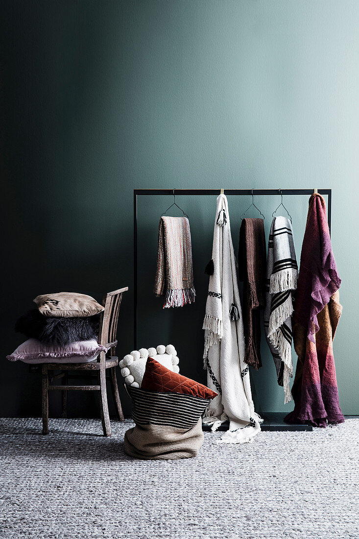 Various blankets and plaids hang on a coat rack