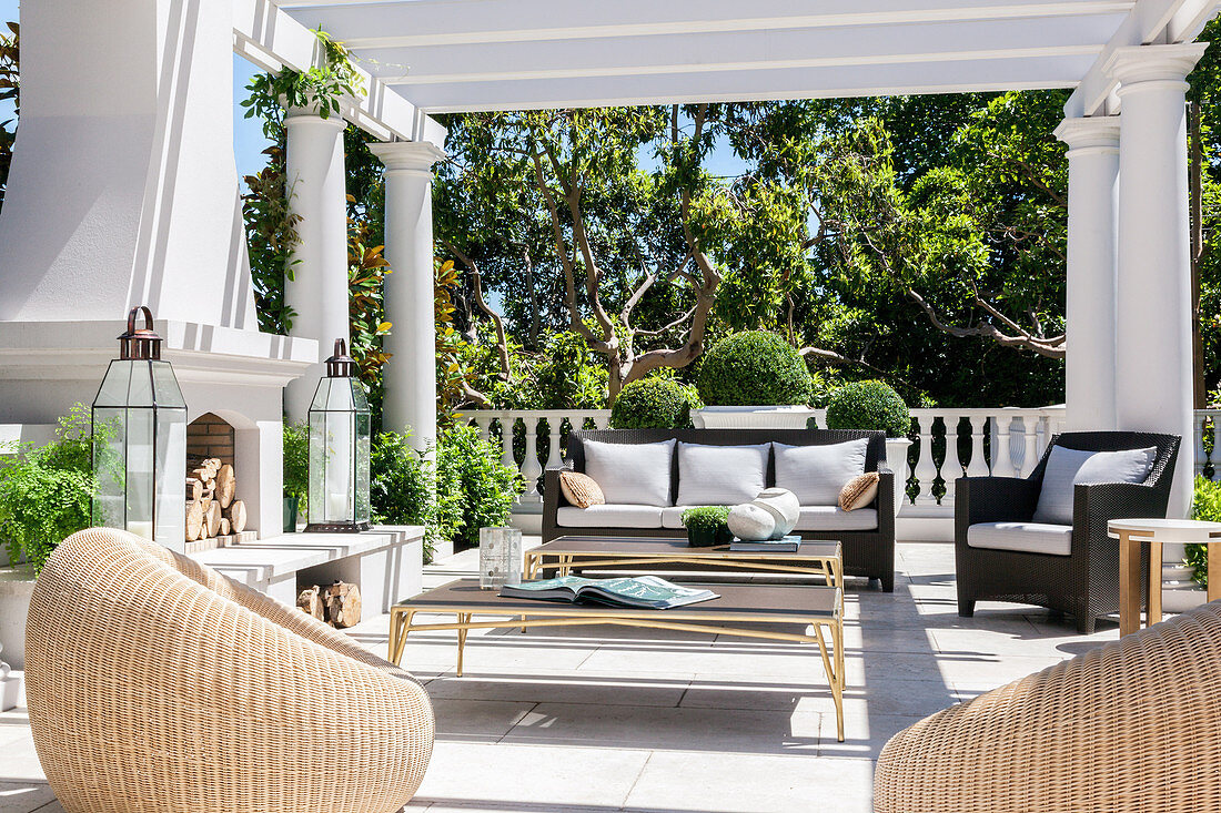 Elegant terrace with wicker armchairs, coffee table, sofa and fireplace
