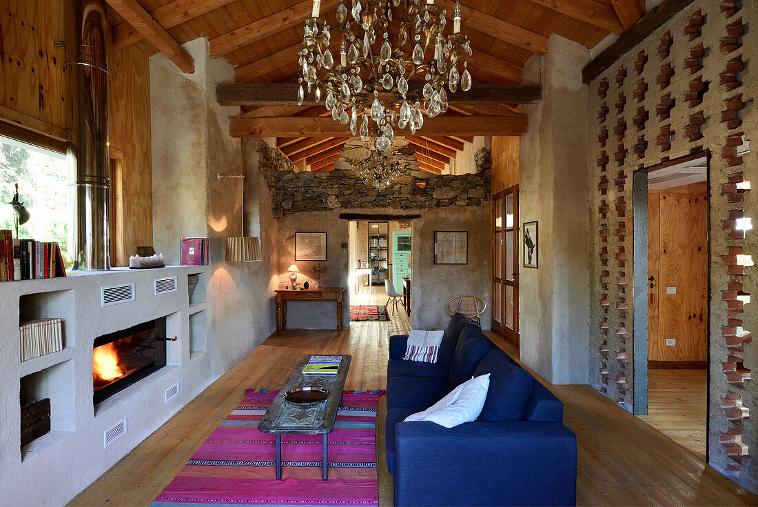 Loungebereich mit Kamin in umgebauter Scheune mit Beton-, Ziegel und Holzwänden
