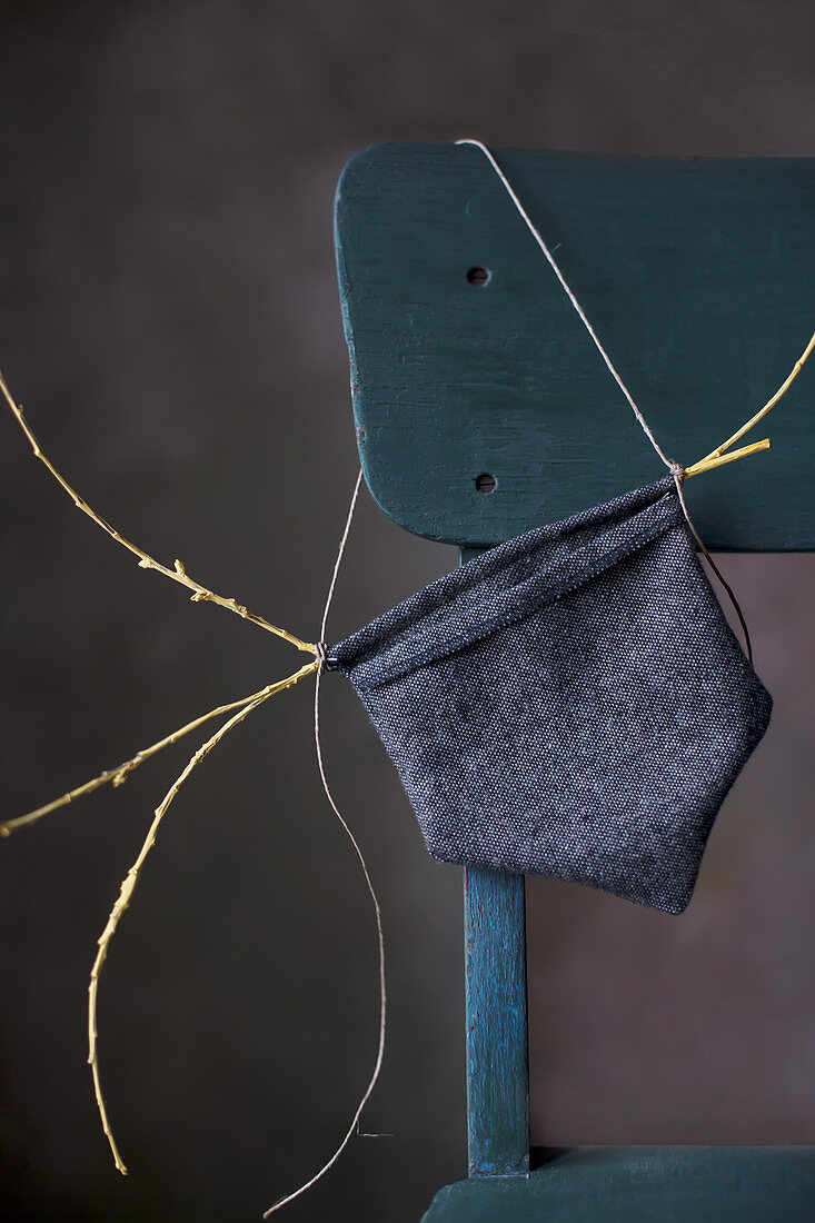 Small hand-sewn bag made from dark fabric on chair backrest
