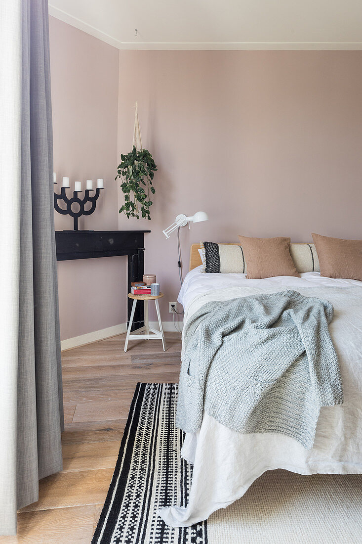 Doppelbett, Pflanzenampel und Kaminkonsole mit Kerzenhalter im Schlafzimmer