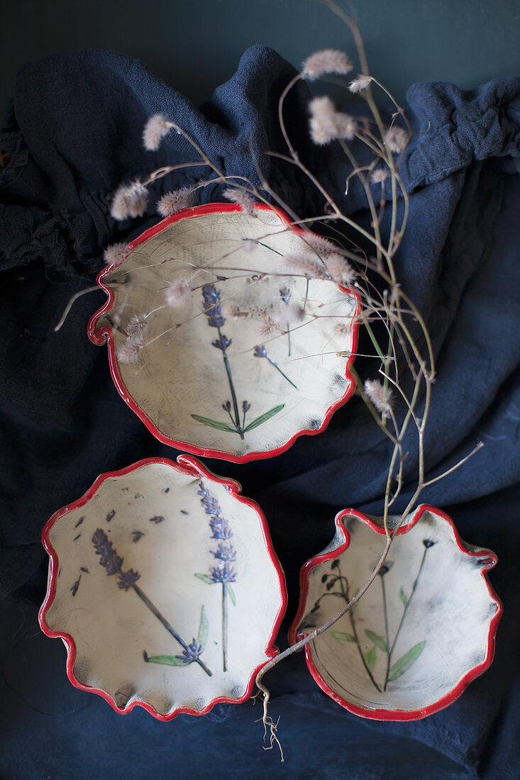 Ceramic bowls with embossed floral motifs and red rims