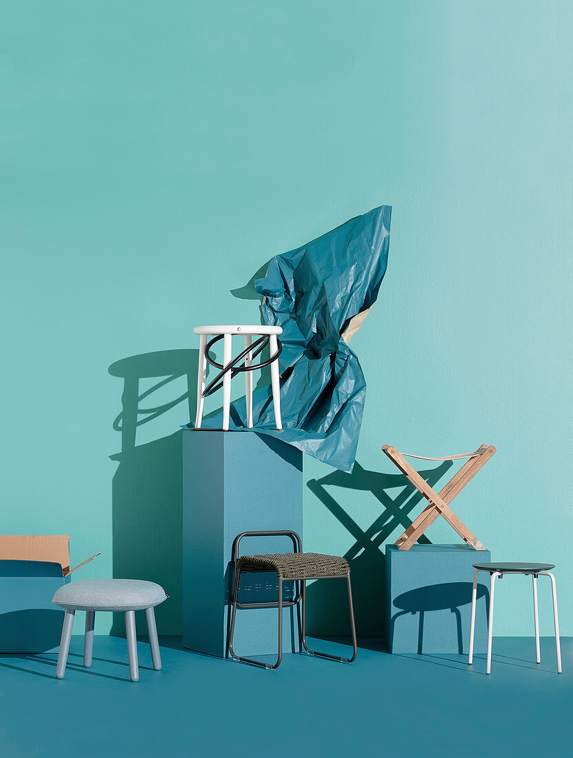 Various stools in front of a turquoise wall