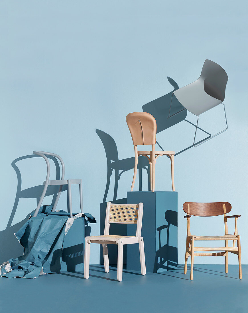 Verschiedene Stühle vor blaugrauer Wand