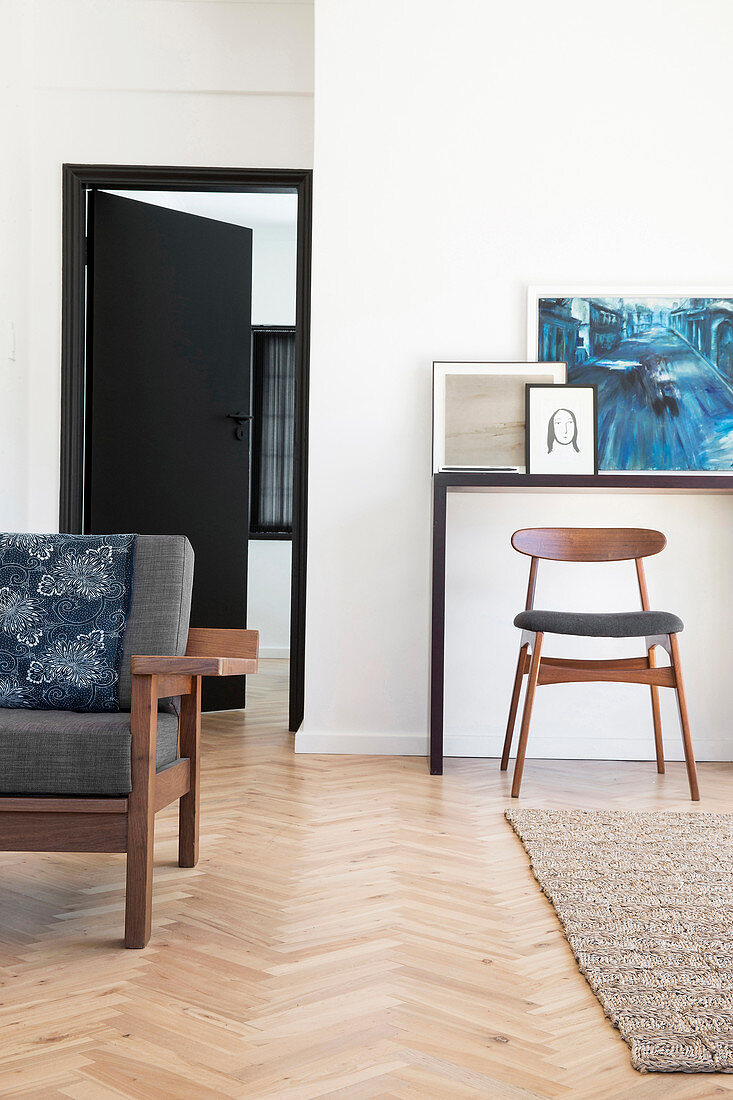 Couch und Stuhl vor Konsole im Wohnzimmer mit Parkettboden im Fischgrätmuster