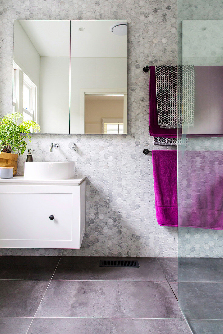 Mirror cabinet, vanity unit and towel rack in tiled bathroom