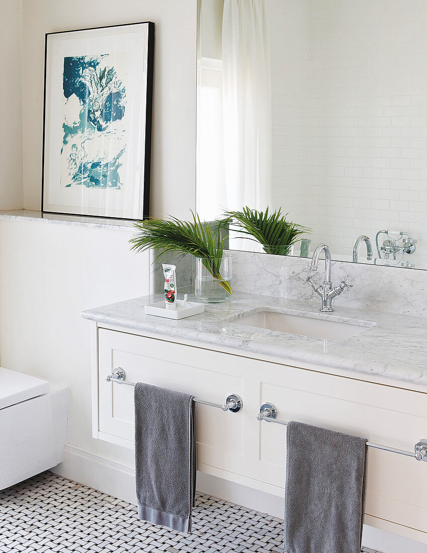 Washstand with marble top and two towel rails in bright bathroom