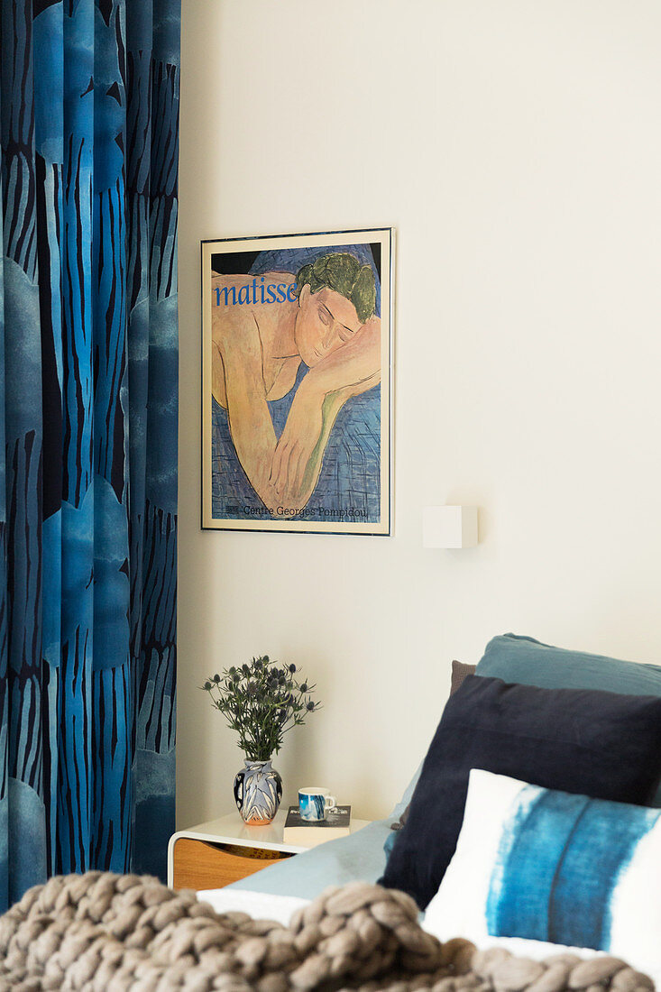 Blue patterned curtains next to the bed with a modern bedside table