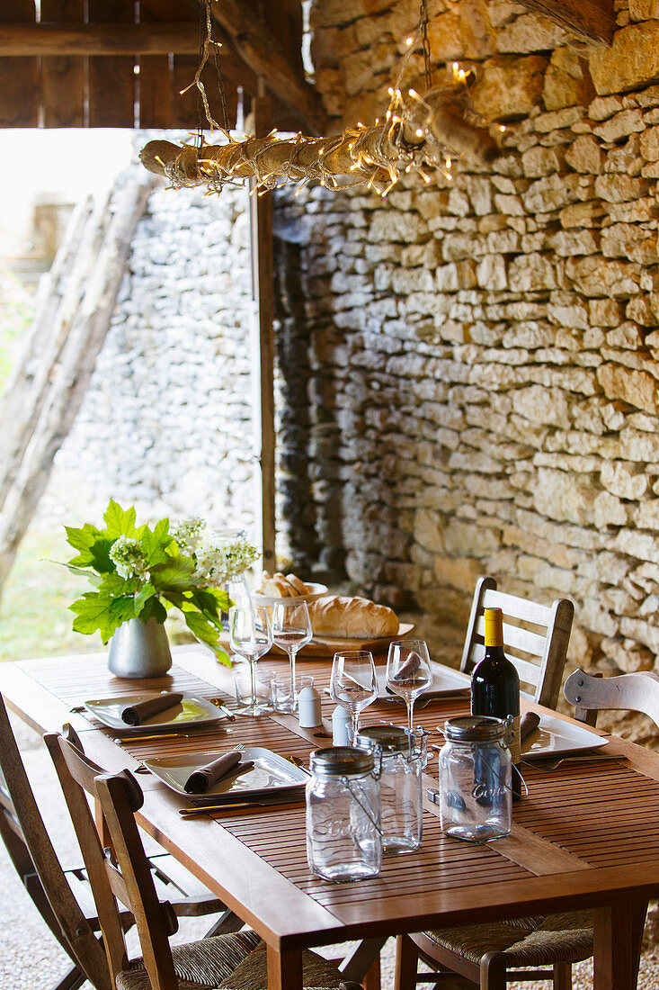 Set table in converted barn with stone wall