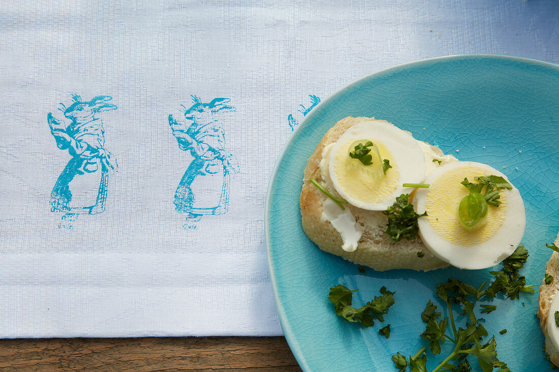 Baguette with sliced egg on Easter-themed tablecloth with rabbit motif