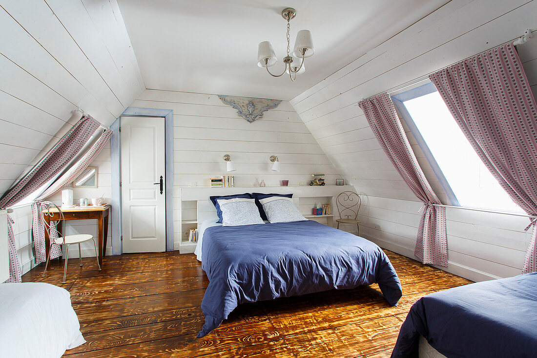Ländliches Schlafzimmer unter dem Dach mit weißen Bretterwänden